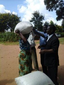 Fr. Chinkanda helping a beneficiary to lift a bag of Maize