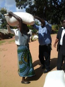 Namakhoma helping a beneficiary to lift a bag of maize